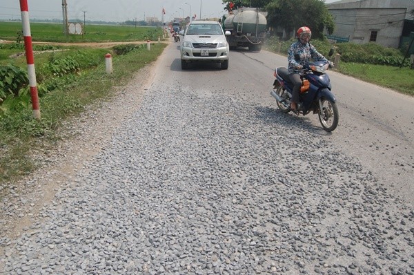 Cả chiều ngang quốc lộ 21B bị phủ kín bởi đá sỏi, vật liệu xây dựng gây nguy hiểm cho người tham gia giao thông