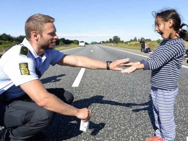Bức ảnh cảnh sát chơi đùa với bé gái tị nạn gây "sốt" ảnh 1