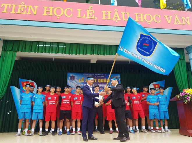 Thầy Hiệu trưởng Nguyễn Công Sở (phải) trao lá cờ thể hiện tinh thần mãnh liệt của THPT Lê Văn Thiêm cho đội bóng